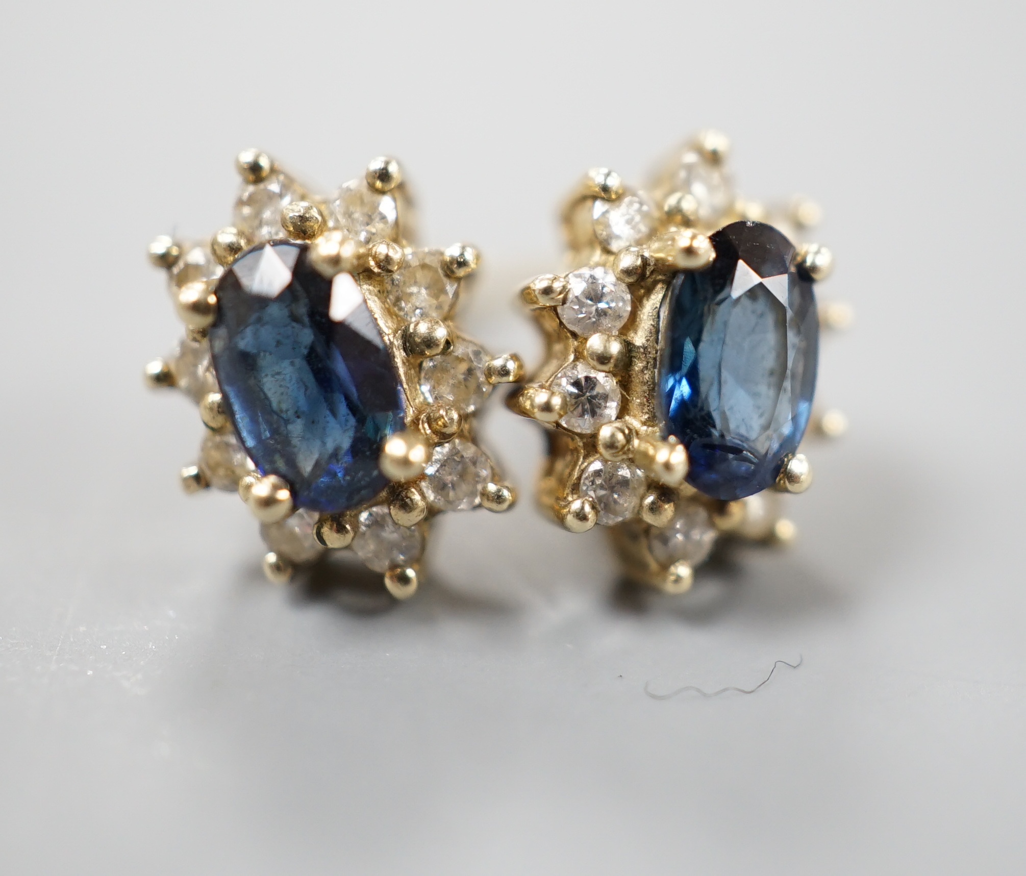 A pair of modern 9ct gold, sapphire and diamond chip set oval cluster earrings, gross 1.3 grams.